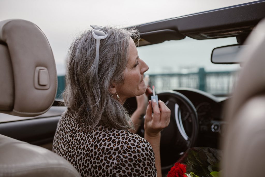 Žena v strednom veku sa maľuje v aute